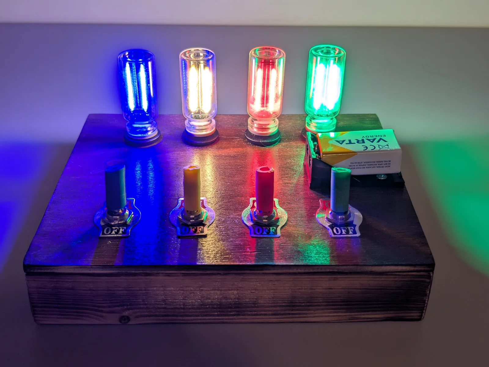 The Edison Edition prototype from the front, four filament bulbs lit in blue, warm white, red and green above four toggle switches